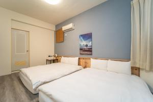 two white beds in a room with a window at Qilin Valley in Puli