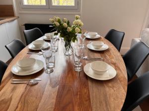 une table en bois avec des assiettes, des verres et un vase de fleurs dans l'établissement Chez Louisa-Maria, à Dijon