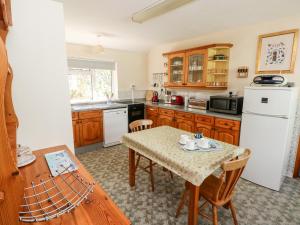 a kitchen with a table and a white refrigerator at Otter Cottage in Newport Pembrokeshire