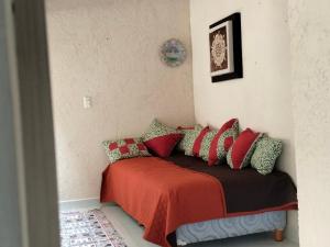 - un lit avec des oreillers rouges et verts dans l'établissement Casa de campo, Huasca Hidalgo, à Huasca de Ocampo