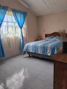 - une chambre avec un lit et une fenêtre avec des rideaux bleus dans l'établissement Casa de campo, Huasca Hidalgo, à Huasca de Ocampo