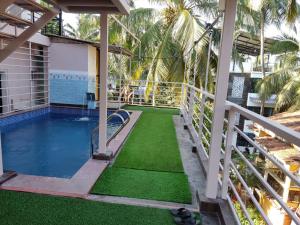 a balcony with a swimming pool and green grass at Bliss Holiday Inn Goa in Calangute