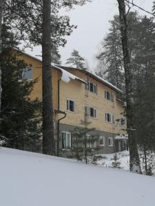 un bâtiment dans la neige avec des arbres devant lui dans l'établissement YH Lappeenranta, à Lappeenranta