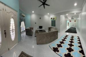- un salon avec un ventilateur de plafond, un canapé et un tapis dans l'établissement Casa Indera, à Kampung Bota Kiri