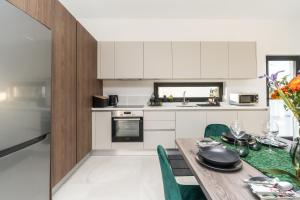 cocina con mesa de madera y sillas verdes en Tsiolakki Homes Luxury Villas, en Protaras