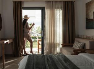 Una donna in piedi in una stanza d'albergo che guarda fuori dalla finestra di Bungalows Iphigenia a Pefkohori