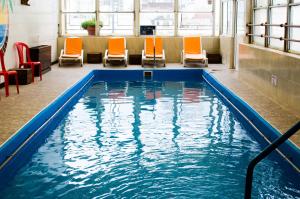 una piscina con sedie arancioni in un edificio di San Remo Grand Hotel a Mar del Plata