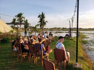 a group of people sitting at tables by a river at Onederz Siem Reap in Siem Reap
