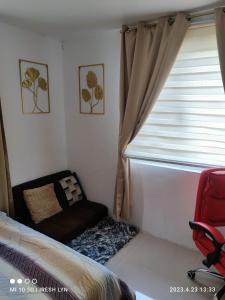 a bedroom with a window and a red chair at iConnect Your Home Away From Home in Tagum