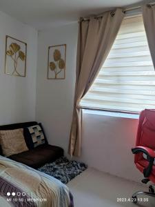 a bedroom with a window with a couch and a chair at iConnect Your Home Away From Home in Tagum