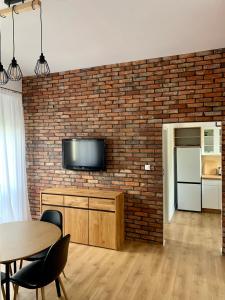 a living room with a brick wall with a television at Apartament Pod Haffnerem in Sopot