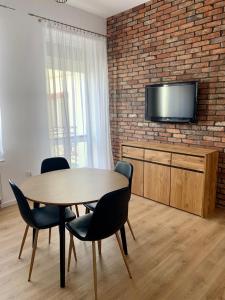 a dining room with a table and chairs and a brick wall at Apartament Pod Haffnerem in Sopot