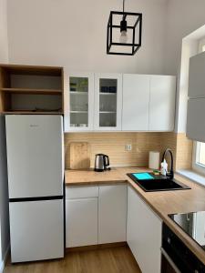 una cucina con armadietti bianchi e frigorifero bianco di Apartament Pod Haffnerem a Sopot