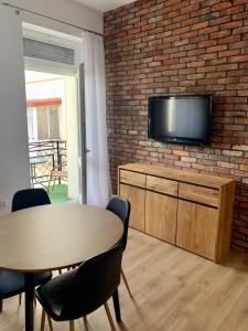 un soggiorno con tavolo e TV su un muro di mattoni di Apartament Pod Haffnerem a Sopot