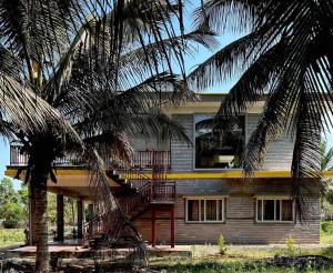 a house with palm trees in front of it at Kashi Farm House in Channarāyapatna