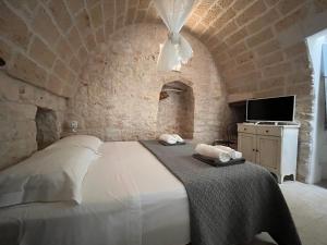 een slaapkamer met een groot wit bed in een stenen muur bij Trullo Al Guappo d'Oro in Ostuni