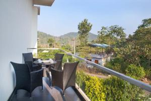 a balcony with chairs and a table with a view at StayVista at Ivory Hill Madikeri including breakfast 3 Bhk Villa in Madikeri