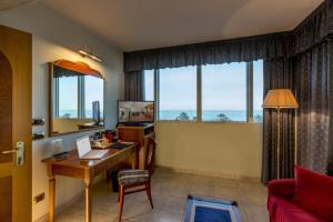 un soggiorno con scrivania, tavolo e finestre di Hotel Ambassador a Tortoreto