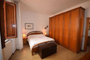 1 dormitorio con 1 cama y un gran armario de madera en Appartamento Santa Barbara, en Scarlino
