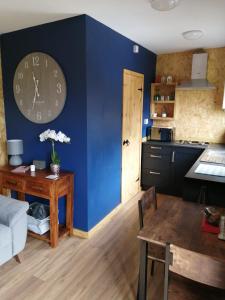 uma sala de estar com um relógio numa parede azul em Lakes and Eden Valley. Thornhill Cabin em Long Marton