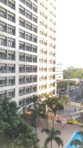 a large white building with palm trees in front of it at Cozy Home 1 bedroom in Manila