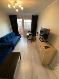 a living room with a blue couch and a tv at Apartament na Broniewskiego in Gdańsk