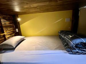 a bedroom with a white bed with a yellow wall at Lapis Restaurant and Hostel in Vũ Lâm