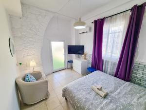 1 dormitorio con cama, silla y cortinas moradas en Aladdin's Hostel en Lárnaca