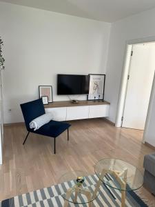 uma sala de estar com uma televisão e uma cadeira azul em APARTMAN IRIS em Banja Luka