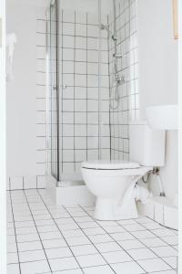 a white bathroom with a toilet and a shower at Bookinn B&B Vilnius' Old Town in Vilnius +46 photos