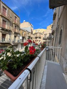 - un balcon avec des fleurs rouges sur une rue de la ville dans l'établissement Casa di Giovi, à Caltagirone