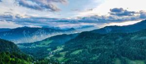een uitzicht op een vallei met bomen en bergen bij Dwarfs cabin overlooking Julian Alps near Bled in Jesenice