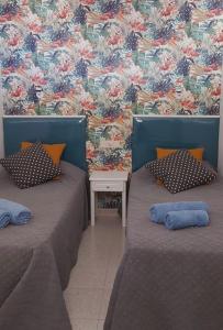 two beds in a room with a floral wall at Playa del ingles Tamaran apartamento 509 in Maspalomas