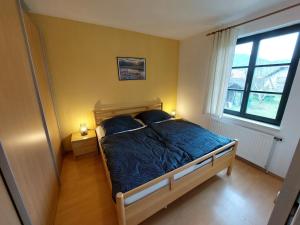 Schlafzimmer mit einem Bett mit blauer Bettwäsche und einem Fenster in der Unterkunft Ferienhaus in der Wachau in Rossatzbach