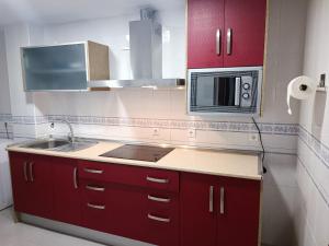 a kitchen with red cabinets and a sink and a microwave at ALOJAMIENTO VIVAL PINEDA in Baeza