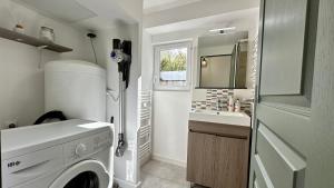 een wasruimte met een wasmachine en een wastafel bij L'Indépendant in Nemours