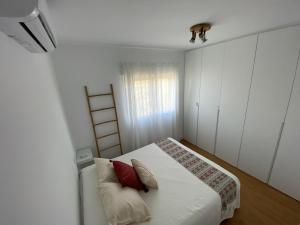 um quarto branco com uma cama com almofadas vermelhas em Tu casa en El Cabo em Cabo de Gata