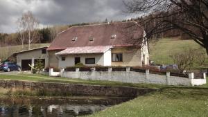 a white house with a red roof next to a pond at Ranch Eden, Jeseník in Jeseník