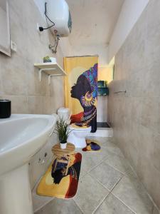 a bathroom with a toilet with a painting on the wall at COZY STUDIO CLOSE TO THE BEACH! in Santa Maria