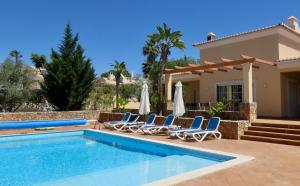 a villa with a swimming pool and lounge chairs at Casa Dos Cedros in Carvoeiro