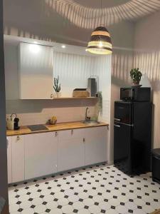 eine Küche mit weißen Schränken und einem schwarzen Kühlschrank in der Unterkunft Bel appartement au cœur de Marseille in Marseille
