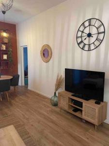 ein Wohnzimmer mit einem TV und einer Uhr an der Wand in der Unterkunft Bel appartement au cœur de Marseille in Marseille