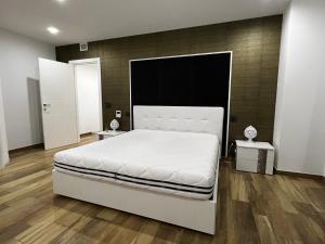 um quarto com uma cama branca e piso em madeira em FRAGAGNANO LUXURY HOME em Fragagnano