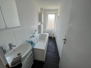 a white bathroom with a sink and a tub at Five O - Familie Meeresleuchten - 3 Schlafzimmer in Wismar