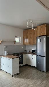 una cocina con nevera de acero inoxidable y armarios de madera en Malina Guest House en Bosteri