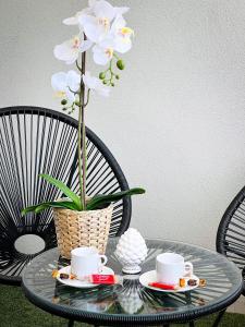 un tavolo di vetro con due tazze e un vaso con fiori di La Costa B&B a Flumini di Quartu