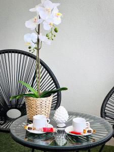 uma mesa de vidro com duas chávenas e um vaso com flores em La Costa B&B em Flumini di Quartu