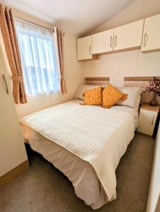 a small bedroom with a large bed with orange pillows at Peacehaven, Ynyslas, Borth in Borth
