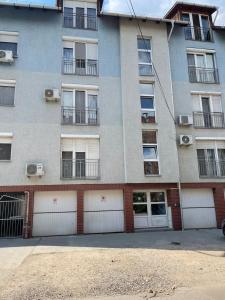 un edificio de apartamentos con puertas y ventanas blancas de garaje en Noemi Appartman Szeged, en Szeged