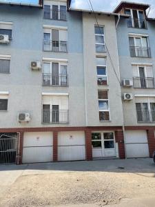 een appartementengebouw met witte garagedeuren en ramen bij Noemi Appartman Szeged in Szeged